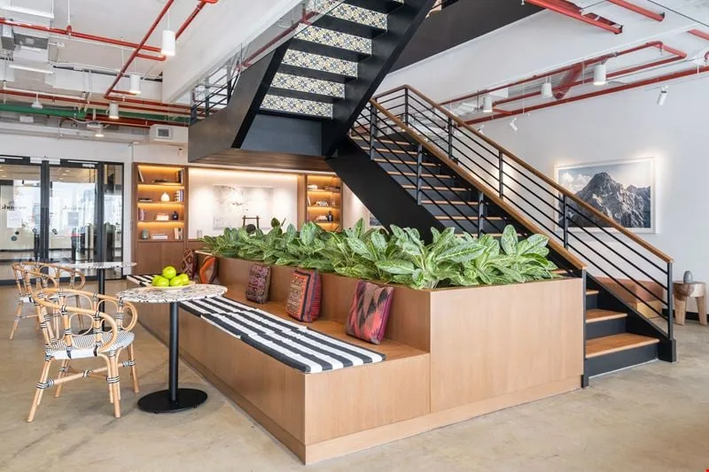 Sunlit lounge inside a Bangkok coworking space with long tables and glass walls